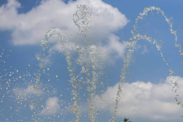 Selective focus on water drops of fountain on sky background.
