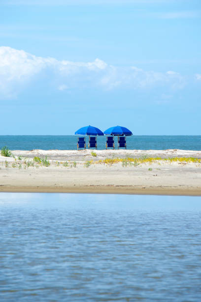 Beach chairs View of two blue beach chairs with umbrellas in front of the ocean. kiawah island stock pictures, royalty-free photos & images