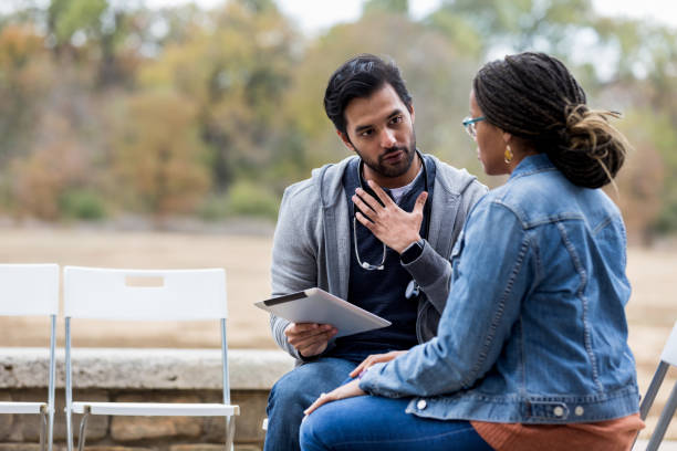 Volunteer male nurse gestures while asking clinic patient questions