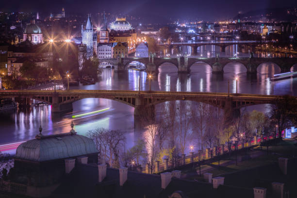 prague panorama with bridges, boat motion and vltava river at night – czech republic - prague mirrored pattern bridge architecture imagens e fotografias de stock