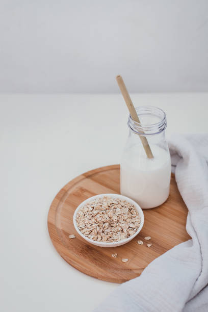 istock Non dairy alternative vegan oat milk in bottle with bamboo eco zero waste straw and fresh oats on wooden tray. Gluten and lactose free products. 1267610011