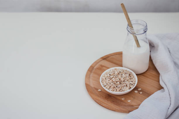 istock Non dairy alternative vegan oat milk in bottle with bamboo eco zero waste straw and fresh oats on wooden tray. Gluten and lactose free products. 1267610016