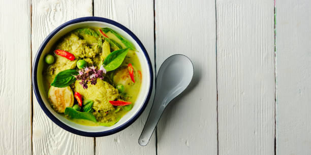 Famous internationally renowned Thai green coconut curry 'Gaeng Keow Wan Gai', with chicken in a bowl with serving spoon.