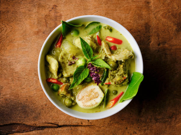 célèbre de renommée internationale thai curry de noix de coco vert 'gaeng keow wan gai', avec du poulet dans un bol fixé sur un vieux fond en bois usé. - culture thaïlandaise photos et images de collection