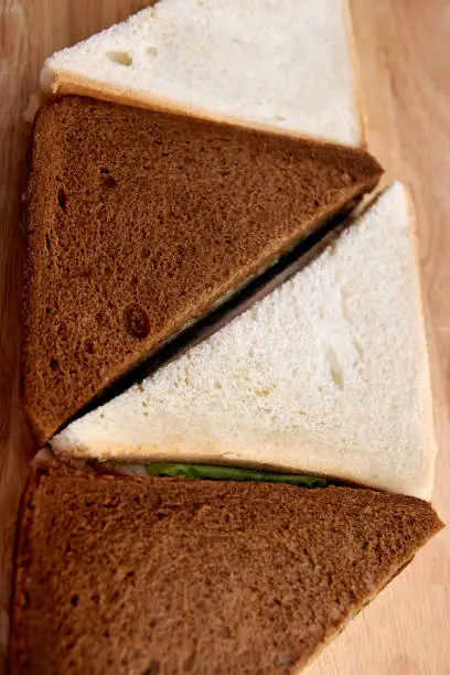 Sandwich with ham. White and black bread. Green salad