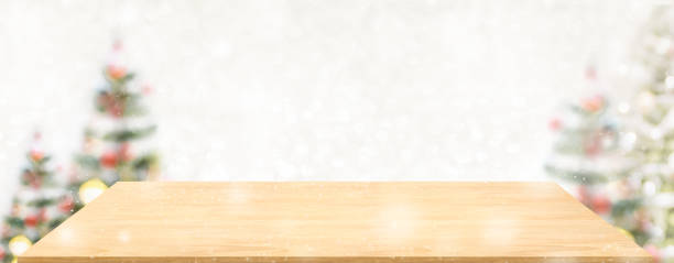 istock Perspective wood table with blur Christmas tree decorate string light and blue bokeh with snow light.Panoramic wooden countertop banner mock up for product display greeting card design online content 1267618265