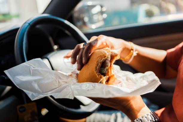 Man eating hamburger in car. stock photo