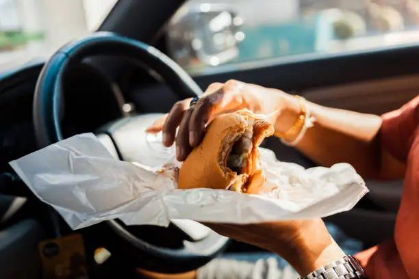 Man eating hamburger in car.