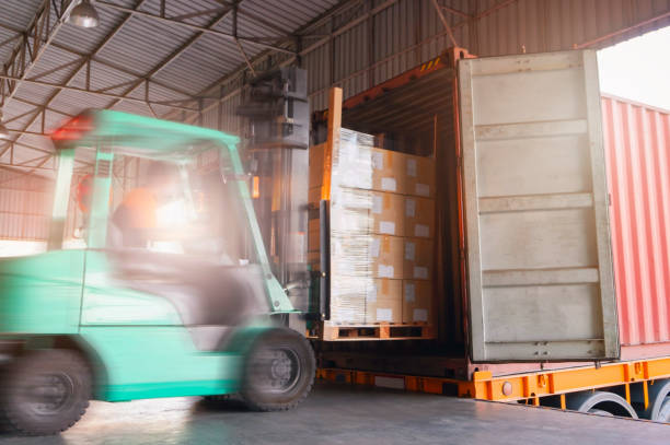 istock Motion blur of forklift driver loading shipment goods pallet into container truck at warehouse dock. Cargo freight, Logistics and transportation. 1267625532