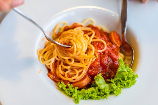 istock Spaghetti on a fork. Girl use fork with spaghetti. Pasta with red sauce. 1267627573