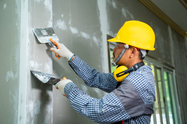 Construction industry worker using a putty knife and leveling in house under reconstruction.