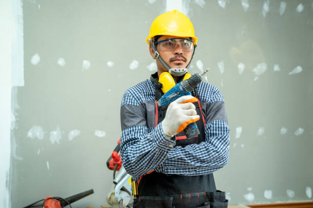 istock Construction worker using a putty knife with trowel plastering a wall in new house 1267627692