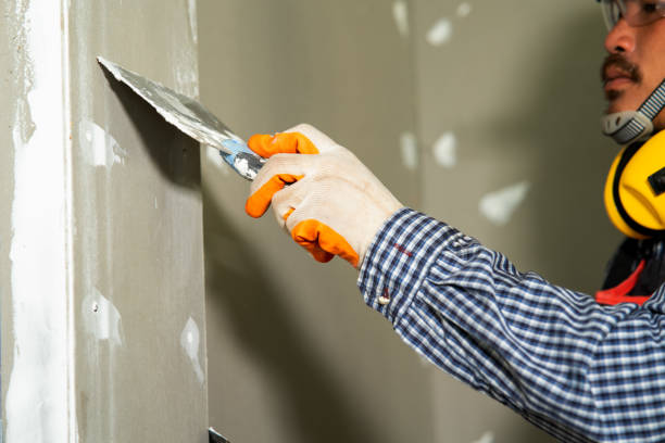 istock Construction worker using a putty knife with trowel plastering a wall in new house. 1267627695