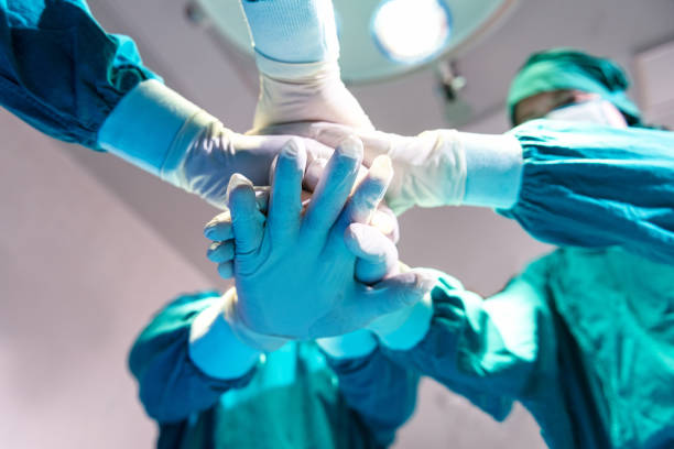 istock Group Surgeon doctor joining hands before Patient surgery in hospital operating theater.  Teamwork medical doctor working  performing surgery 1267628362