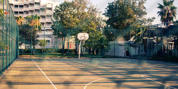 empty basketball court behind metal fence in early morning time outside