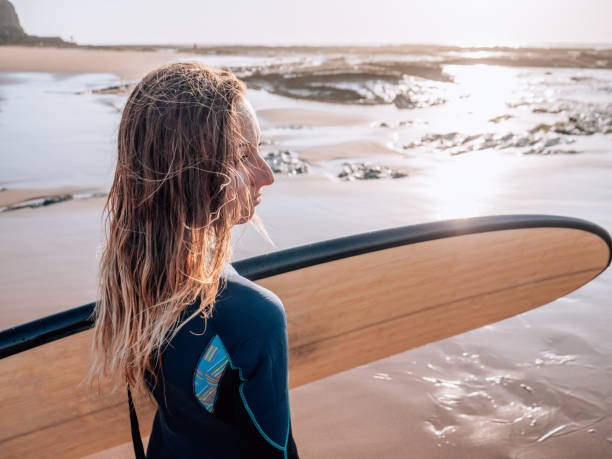 istock Woman with surfboard on beach watching waves in the morning 1267635064