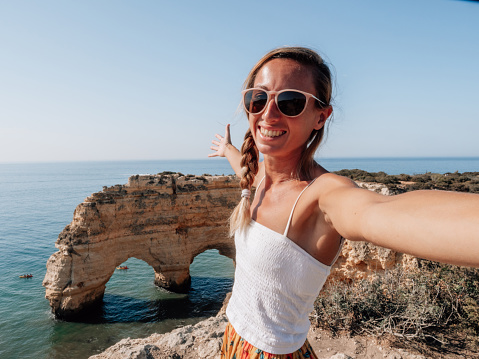 Happy girl take selfie portrait with the Portuguese coastline