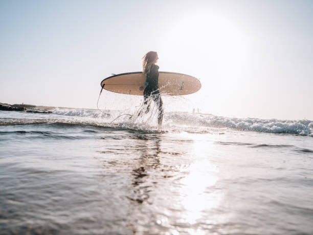 istock Surfer woman runs on the beach at sunrise ready for a morning session 1267635580