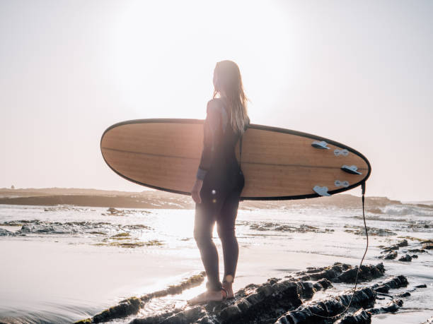 istock Woman with surfboard on beach watching waves in the morning 1267635659