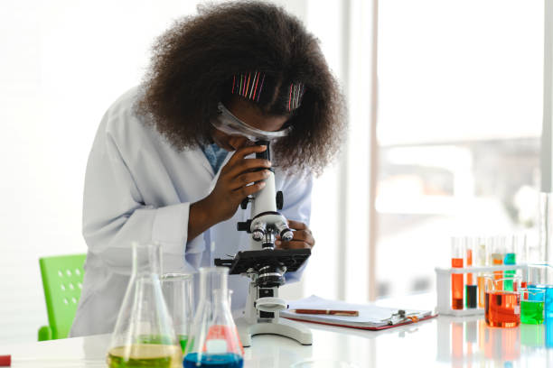 African american girl students learning and doing a chemical experiment and using microscope in science class on the table.Education concept African american girl students learning and doing a chemical experiment and using microscope in science class on the table.Education concept african american scientist stock pictures, royalty-free photos & images