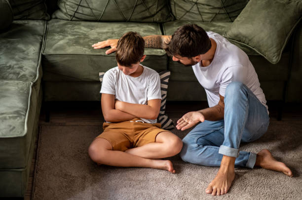 Father and son spend time together at home in the living room, they talking stock photo