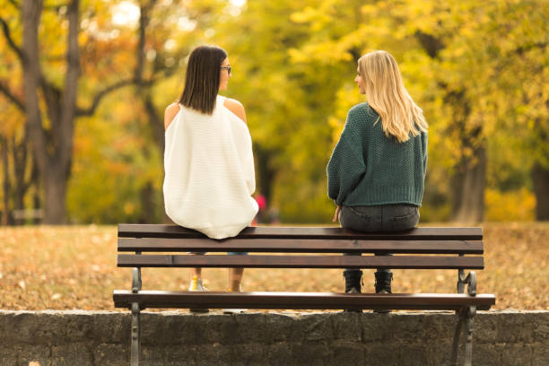 istock Two young women sittin on the bench and talking 1267639581