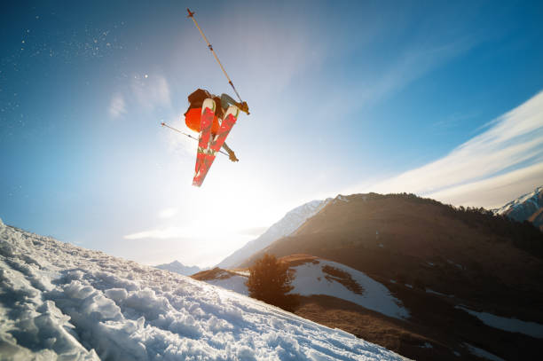 istock man skier in flight after jumping from a kicker in the spring against the backdrop of mountains and blue sky. Close-up wide angle. The concept of closing the ski season and skiing in spring 1267639597