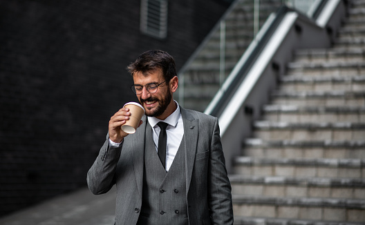 A man goes to work in the morning and drinks coffee while walking down the stairs