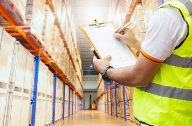 istock Worker holding clipboard his doing inventory management the products on tall shelves. Checking stock, Cargo warehouse storage. 1267648783