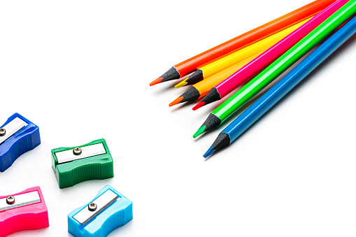 High angle view of six colored pencils and pencil sharpeners isolated on white background. Useful copy space available for text and/or logo. High resolution 42Mp studio digital capture taken with Sony A7rII and Sony FE 90mm f2.8 macro G OSS lens