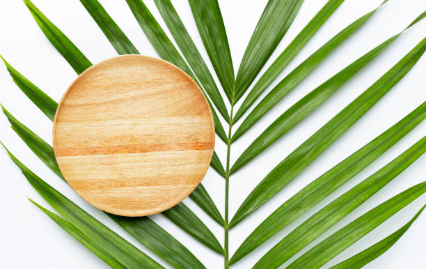 istock Empty wooden plate on tropical palm leaves on white background. 1267660728