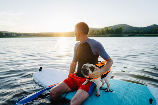 Photo of an active senior man and his dog paddling on the lake; seeking adventure and spending time in nature, far from the city hustle.