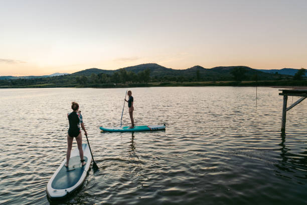 girlfriends stand-up paddling on a lake - women paddleboard bikini surfing imagens e fotografias de stock