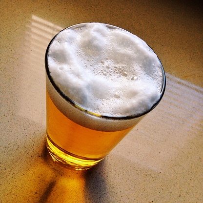 Amber beer on white background, nice frothy head and condensation