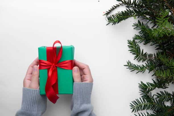 istock Hands hold  Christmas present on a white background with Christmas tree 1267666994
