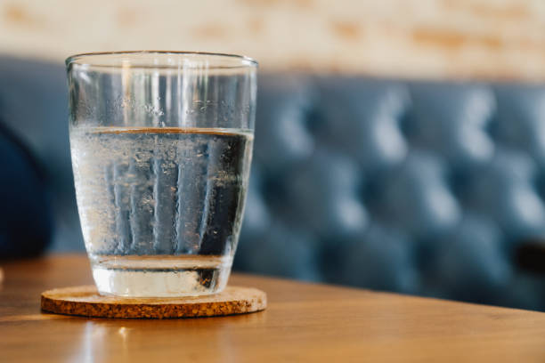 istock Cold water glass in cafe with blue leather sofa as background 1267667848