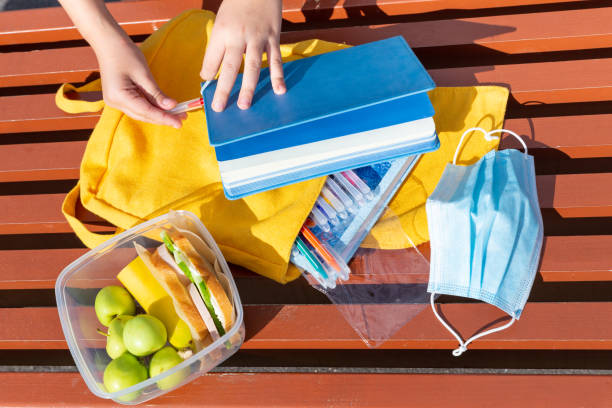 boîte à lunch, mains d’enfant. sandwichs et pommes dans un récipient en plastique. retour à l’école. pause. sac à dos jaune avec fournitures scolaires. - child human hand sandwich lunch box photos et images de collection