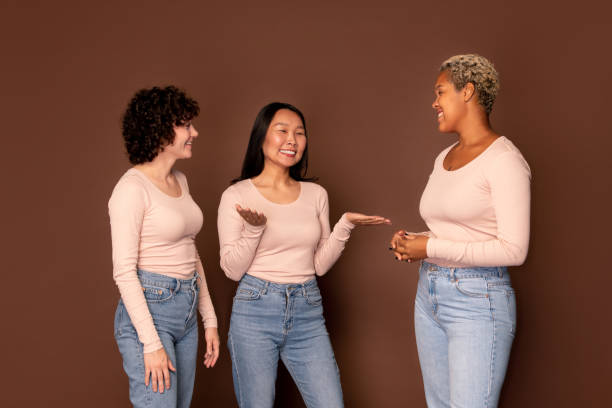 istock Group of young smiling women in white pullovers chatting in front of camera 1267673904