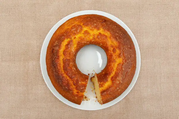 Cornmeal cake (Bolo de Fuba) cut Brazilian style on a white plate. Isolated on jute. Top view. Horizontal shot.