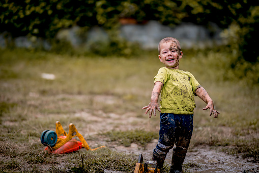 Little boy walks on a muddy road after rain
