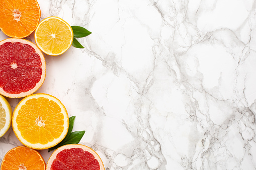Citruses fruits on marble background with copyspace, fruit flatlay, summer minimal compositon with grapefruit, lemon, mandarin and orange top view