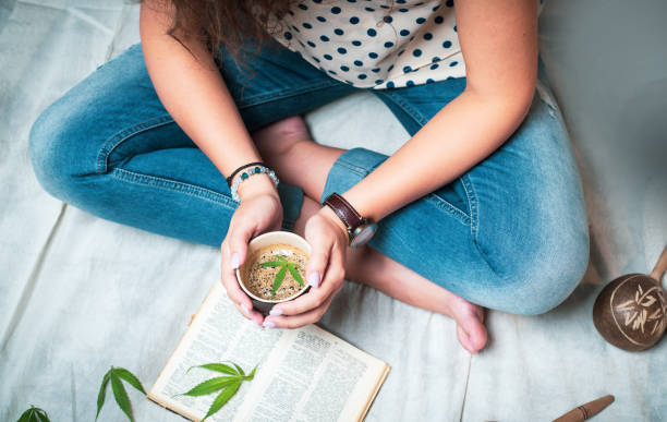 마리화나가 있는 여성은 집에서 책을 읽는 동안 커피를 주입했습니다. - canabis strain 뉴스 사진 이미지