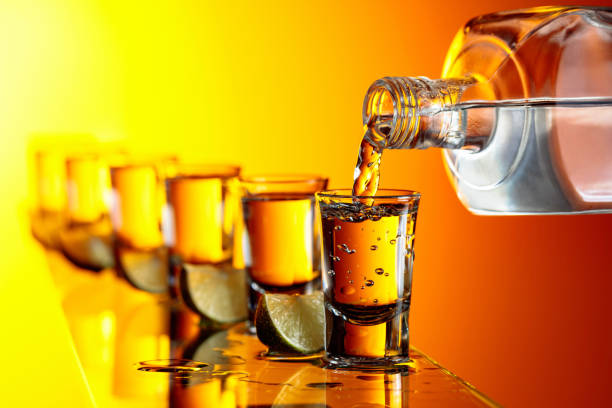 pouring a strong alcoholic drink into small glasses. - hard liqueur imagens e fotografias de stock