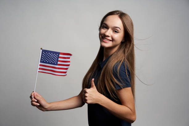 istock Happy female holding America flag and gesturing thumb up 1267680982