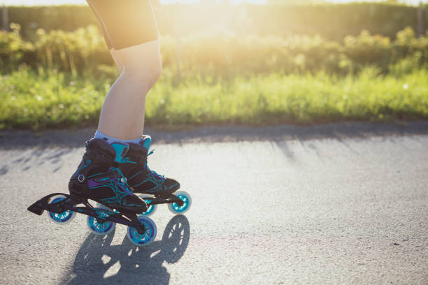 Girl is rollerblading along an asphalt alley in sunny day