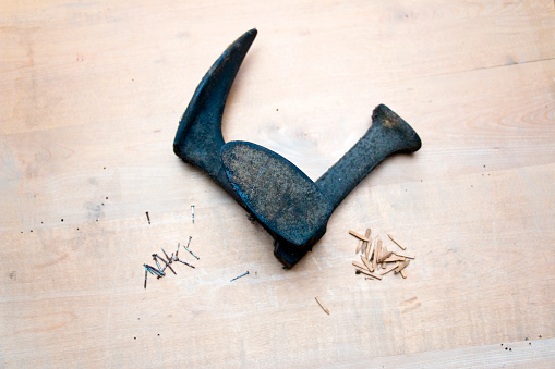 Used Tools. A metal hammer with claw head. A worn marked wooden handle. Top view