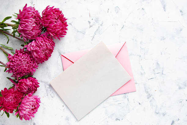istock Pink envelope and flowers on a light concrete background. Mock up invitation, creative greeting card. Flat lay, top view. 1267685796