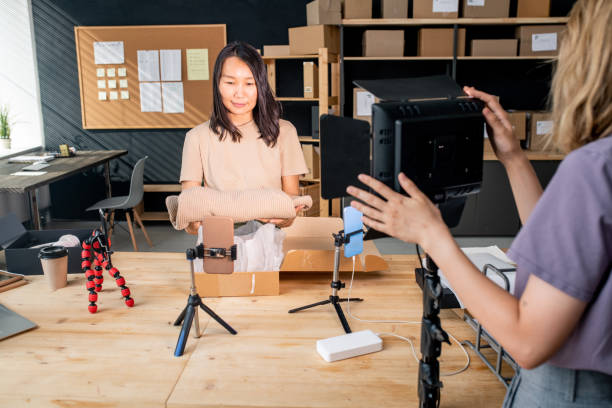 istock Young Asian female packing folded sweater into box while standing by table 1267687436