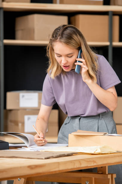 istock Young woman calling one of clients while checking information about order 1267687447