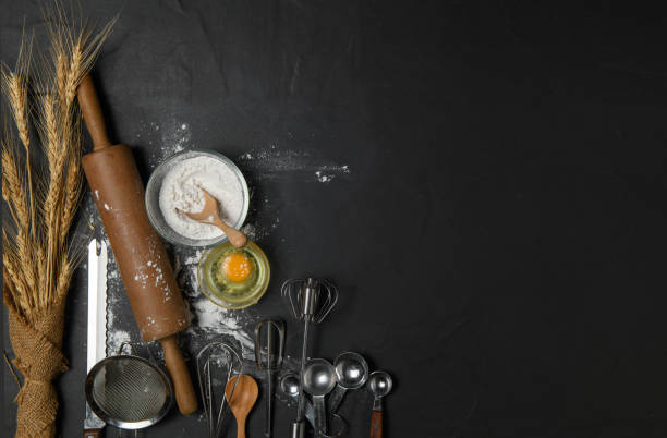 istock fresh eggs and cake flour  with kitchen utensils for pastries on black table, 1267690691